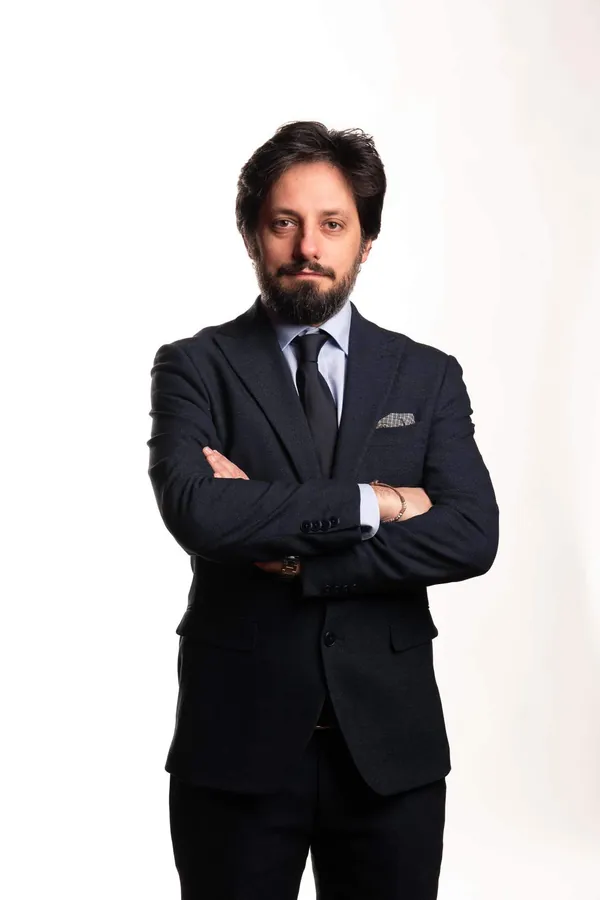 Antonino Polimeni a figura intera su fondo bianco, braccia conserte