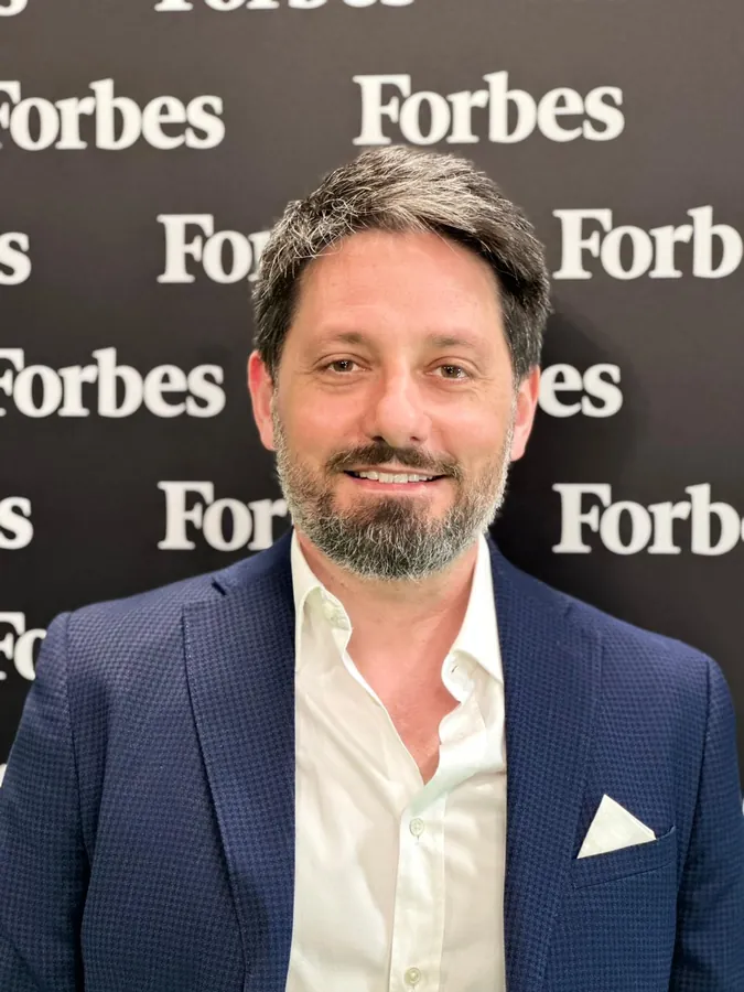 Antonino Polimeni davanti al fondale di Forbes Italia